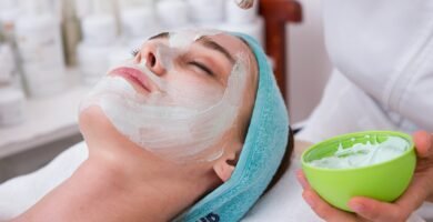 woman lying on blue towel with white cream on face